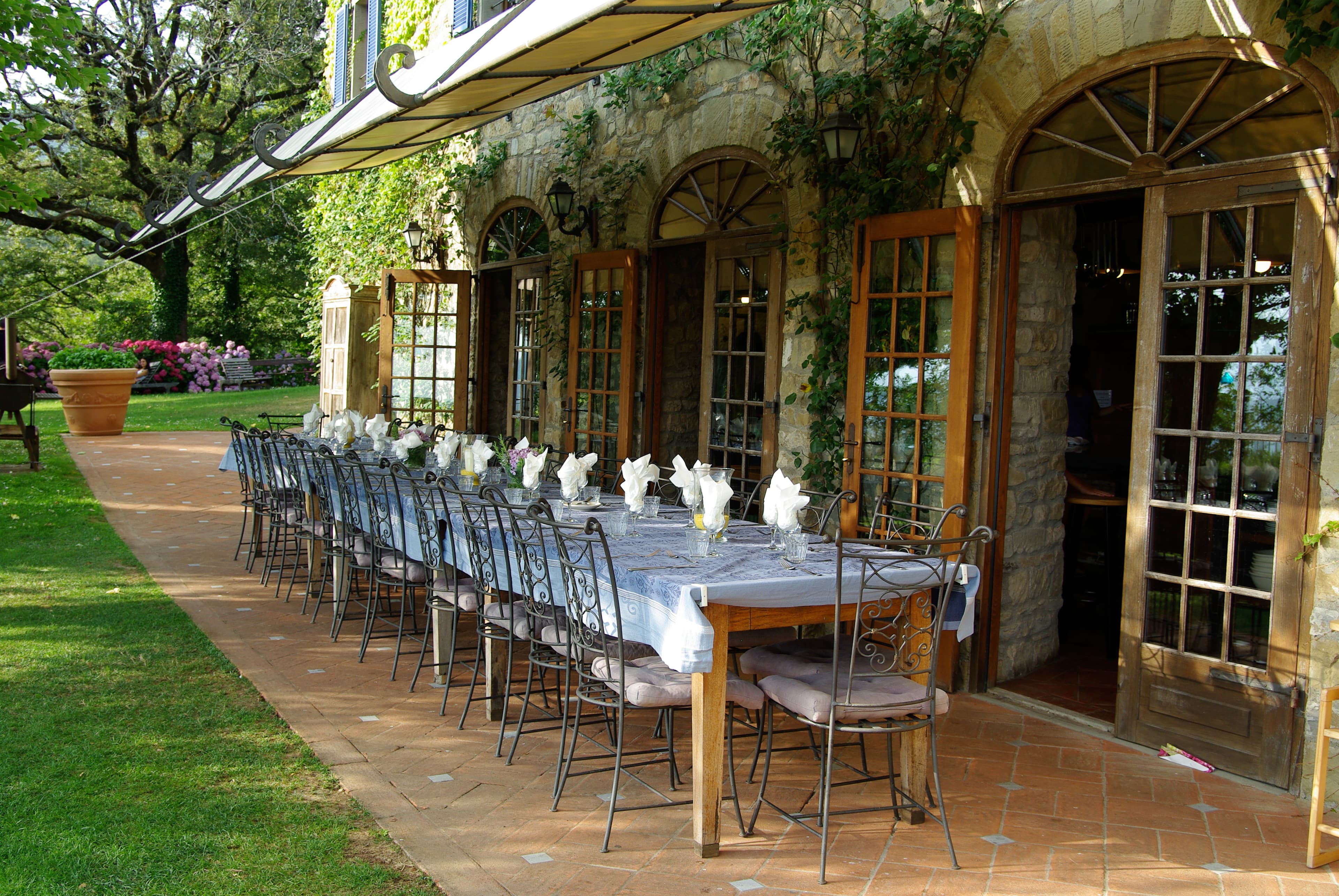 Long dining table with blue linens and white napkins outside a rustic stone building.
